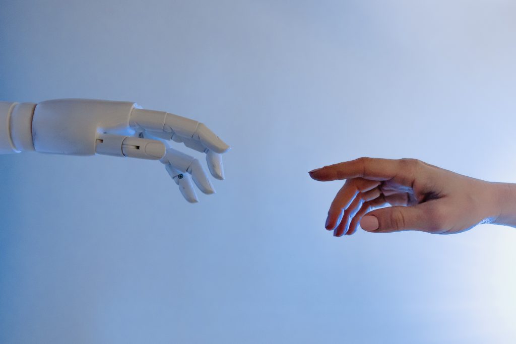 A human and robot hand reaching out to each other.